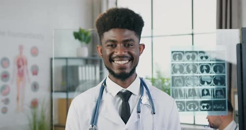 Close up of man doctor in white coat with stethoscope standing in front of camera in clinic lab with