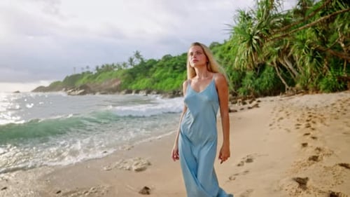 Elegant Woman in Blue Dress Strolls on Sandy Beach Serene Model By Sea Tropical Escape Fashion Shoot