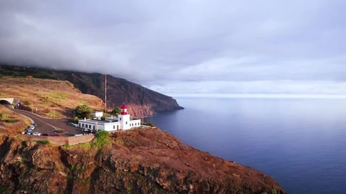 Aerial of a lighthouse on a cliff edge on rocky volcanic coast, Madeira
