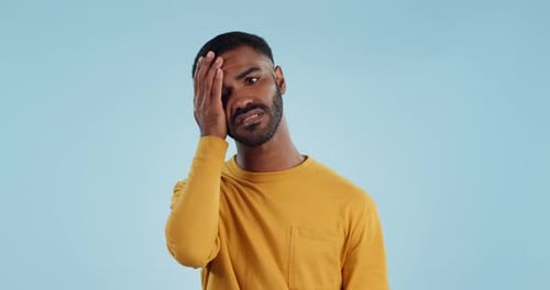 Stress, fail and man in studio with facepalm emoji for stupid mistake or regret on blue background