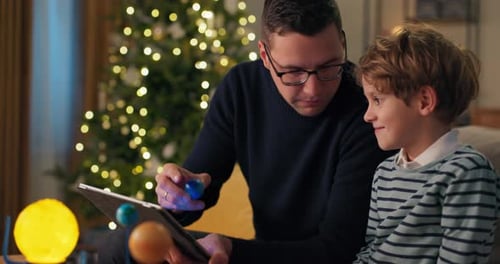 Father and Son Explore Solar System on Tablet