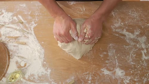 Person Kneading Dough on Wooden Table