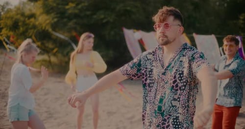 Jeune homme insouciant portant des lunettes de soleil dansant contre des amis