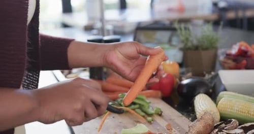 Woman peels carrots at the kitchen counter
