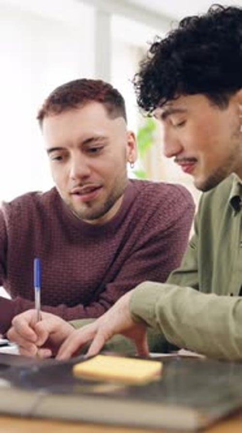 Gay Couple Studying Together Writing on a Notepad Vertical