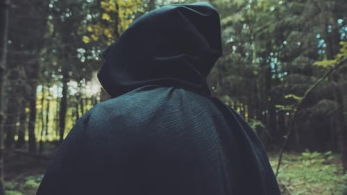 Mysterious Figure Walking in Forest with Black Cloak