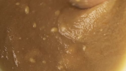 Nahaufnahmenmakro eines Holzspatels, in dem köstliche Pastenzutat gemischt wird, Slomo