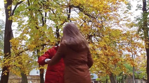 Happy couple spins in autumn park holding hands