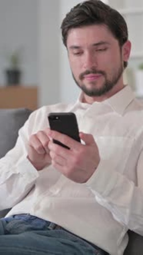 Man Smiles, Celebrates Success While Using Mobile Phone