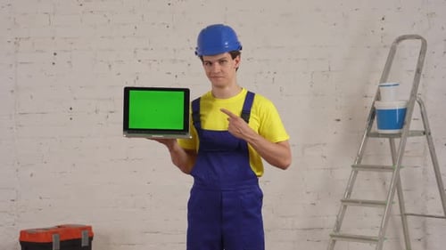 Medium Video of a Young Construction Worker Standing in the Room Holding a Laptop with Advertising