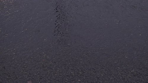 Wasserspray löst sich von den Reifen, wenn Fahrzeuge in der Abenddämmerung durch Regen fahren