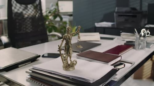 Lady Justice Statuette on Pile of Documents on Office Table