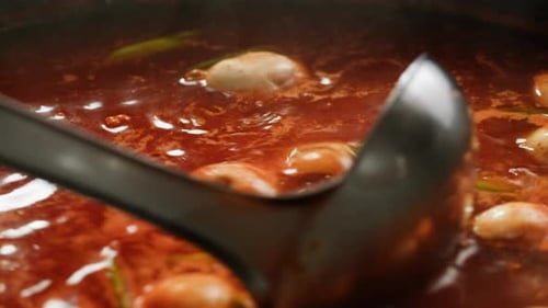 Red Broth with Meatballs Being Served with Ladle