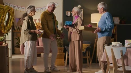 Seniors Exchange Birthday Gifts in a Decorated Living Room