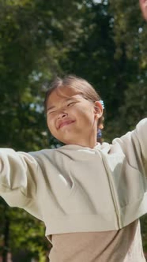 Vertical Portrait of Asian Pre-Teenage Girl Enjoying Soap Bubbles in Green Park