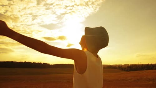Boy Raises His Hands to the Sky on Mars Boy in a Hat Raises Hands to the Sky in the Field Sun Glare