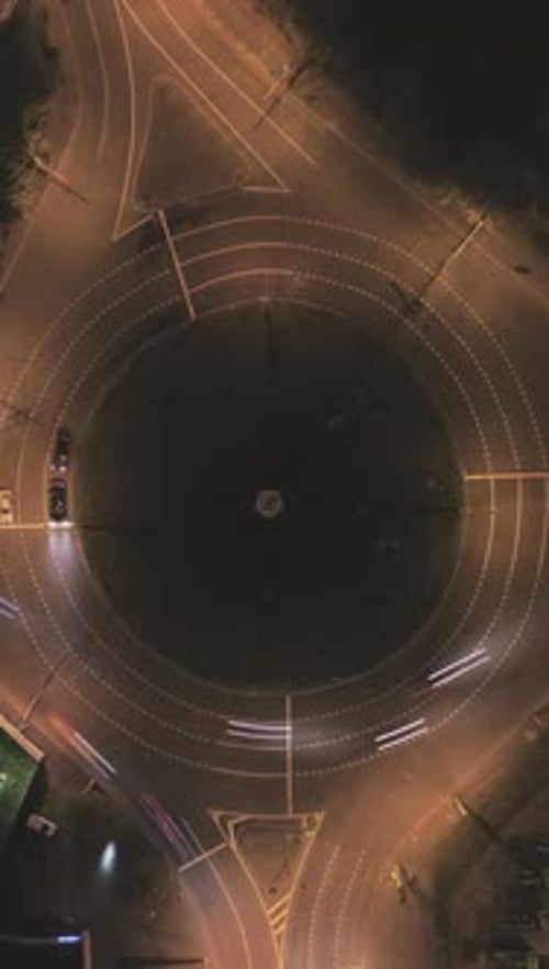Illuminated Roundabout in the City and Cars Traffic at Night Round Crossroad Aerial Time Lapse