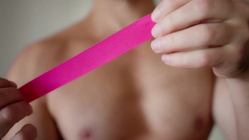 Man Applies Pink Kinesiology Tape to Shoulder