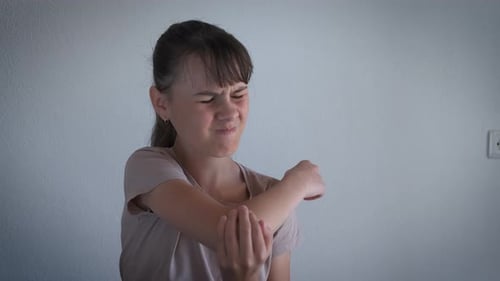 Woman Rubs her Elbow in Discomfort