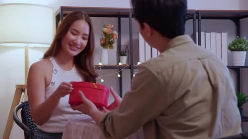 Woman Receives Gift From Man in Home Setting