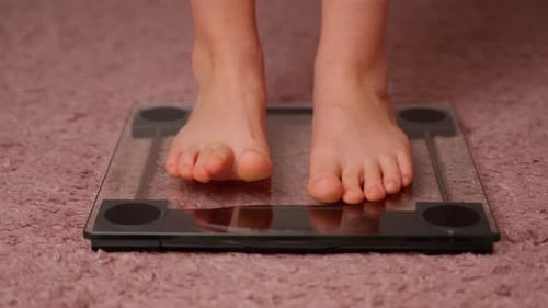 Girl On Scales Measure Weight Close Up. Child Legs Step Bathroom Scale. Fitness Diet Young Person
