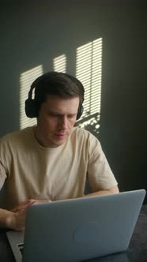 Man Working from Home Using Laptop and Headphones