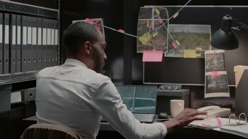Man Reviews Case Evidence at Desk