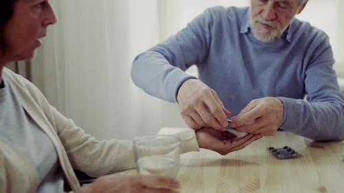 Senior man gives pills to an adult woman