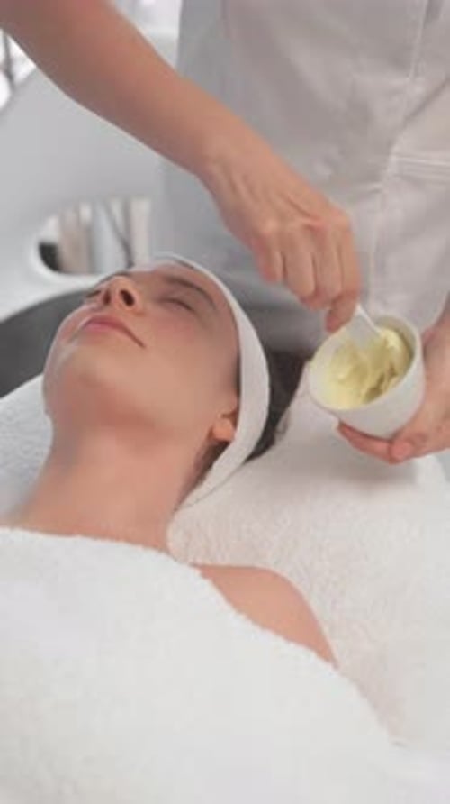 Cosmetologista preparando creme para mulher relaxante na clínica