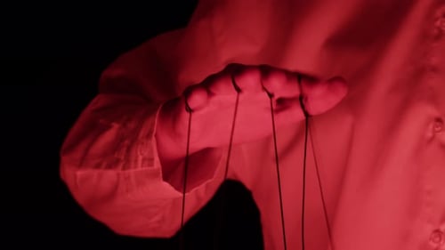 The Puppeteer Controls the Puppets in the Theater in Red Neon Light Closeup Managing People at Work