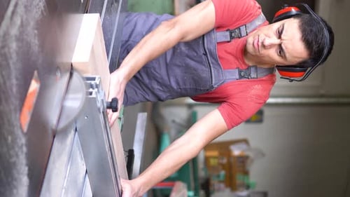 Woodworker Cutting Plank with Table Saw in Workshop