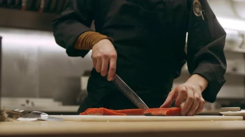 Chef slicing salmon in commercial restaurant kitchen