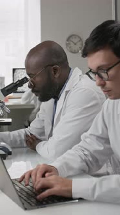 Scientists Collaborating in Lab with Microscope and Laptop