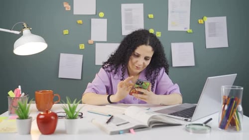 Young Woman Studying with Phone at Desk