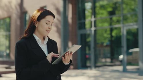 Businesswoman in Formal Suit Uses a Tablet Outdoors for Work Texting and Swiping Apps Office Worker