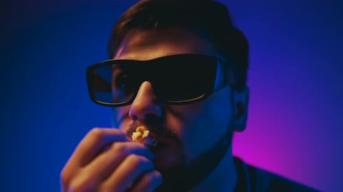 Young Adult Wearing 3D Glasses Eats Popcorn