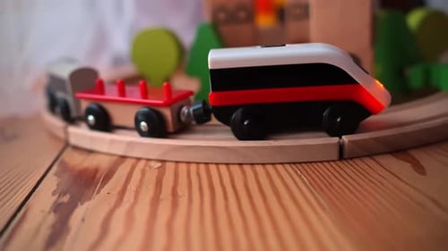 Spielzeugeisenbahn aus Holz, die auf einer geschwungenen Schiene über einer Tischplatte aus Kiefernholz rollt, gemütliche Kinderzimmerszene mit
