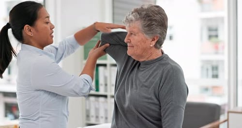Physical Therapist Stretching Arm of Senior Woman