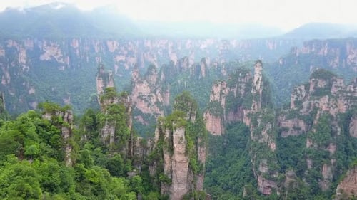 Pináculos rochosos dramáticos se estendem até uma distância nebulosa, aérea de Hunan, China