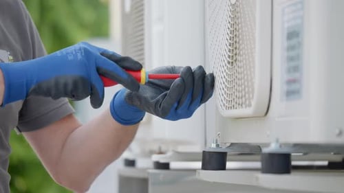 Worker repairing AC unit with screwdriver