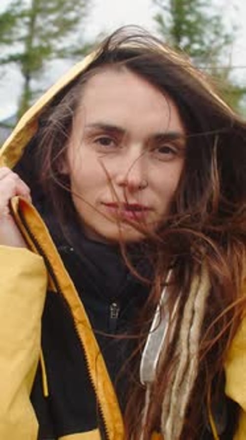 Mujer joven explorando la naturaleza en un impermeable amarillo