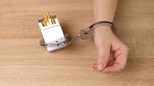 17 cm. Une femme est menottée à un paquet de cigarettes. Concept de dépendance au tabac. C'est dommage de fumer
