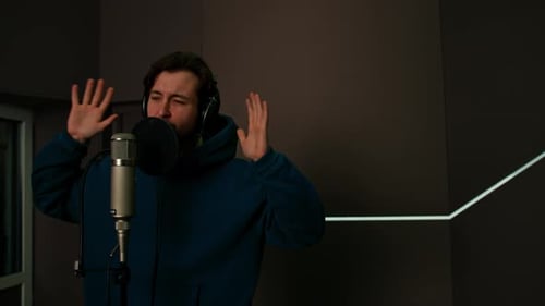 singer with headphones and microphone emotionally recording a new song in a professional studio