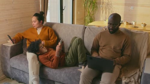 Family Relaxing Together on Couch Using Technology