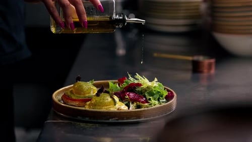 Close Up in a Professional Kitchen on Clean Metal Table a Woman Chef Collects a Salad with Fresh