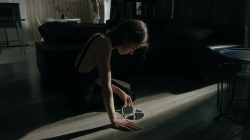 Paranoid Young Woman Taking Shard of Broken Mirror and Looking towards Window
