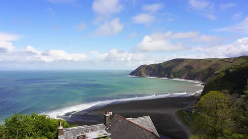 View over Lynmouth Bay from Lynton on a fine summers day showing waves rolling onto the rocky pebble