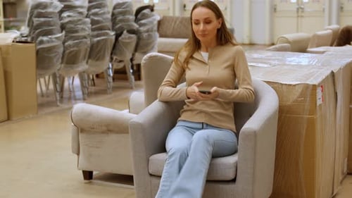 Young Woman is Examining a New Armchair in a Furniture Store