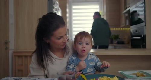 Woman and Baby Eating Breakfast in Kitchen