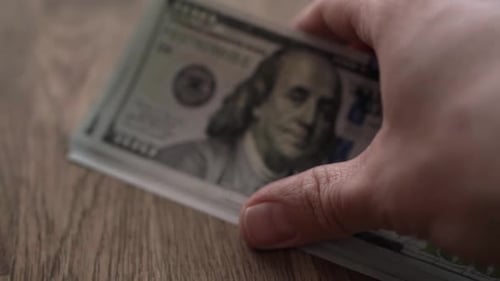 Dollar bills on wooden table close up counting slow motion